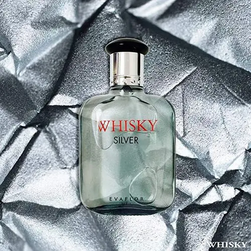 Flacon de parfum Whisky Silver d'Evaflor sur un fond argenté froissé, avec un bouchon noir et une étiquette rouge et argentée